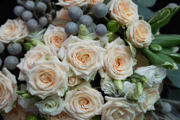 Beautiful wedding bouquet of bushy cream rose, eucalyptus, Brunei, Pittosporum and Lisianthus on a black background.