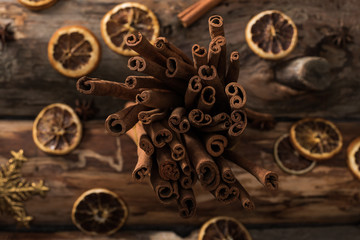 Fototapeta na wymiar top view of dried citrus slices with cinnamon sticks and decorative snowflakes on wooden background