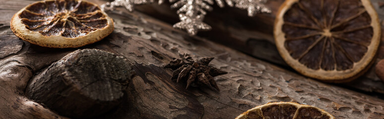 dried citrus slices with anise and decorative snowflakes on wooden background, panoramic shot