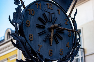 Big black retro metal clock on the modern city street background.