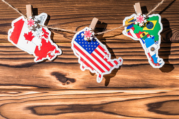 Obraz premium Map (flag) of North, South America, Canada hanging on a rope on wooden clothespins. Rustic Christmas decoration. Wooden boards background. USA. Concept