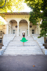 Summer vacation. A girl in a green dress stands on the stairs near the sanatorium. Chkalov in Odessa. - obrazy, fototapety, plakaty