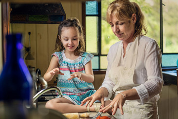 Mature woman teaching her granddaughter while standing in kitchen