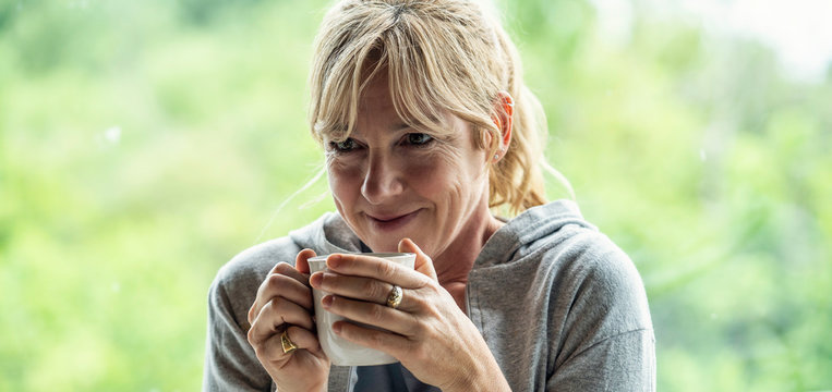 Smiling mature woman having coffee at home
