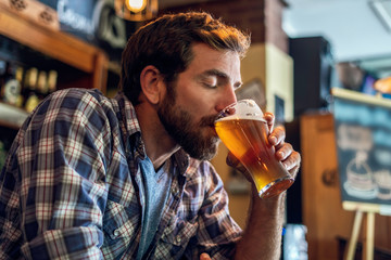 Man with eyes closed drinking beer in the bar