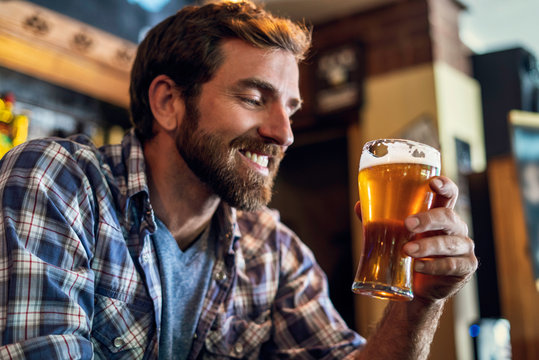 Smiling man looking at beer glass in the bar