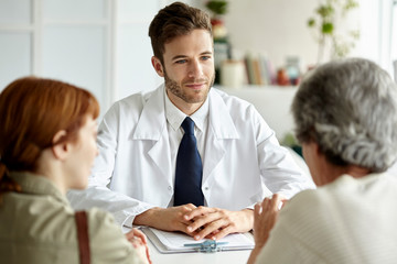 Senior patient talking with doctor, her daughter sitting besides her