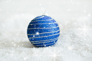 Fototapeta na wymiar Beautiful blue Christmas ball on snow Beautiful Christmas bauble decorations lie on the white fluffy snow. Atmosphere of magic and fairy tales