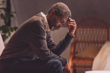 senior, depressed african american man sitting with bowed head