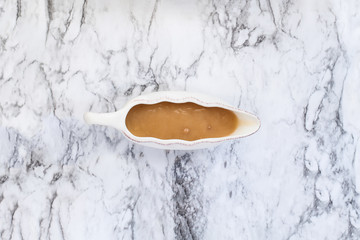 Homemade turkey gravy in a gravy boat or sauceboat ready for Thanksgiving Day. Image shot from high...