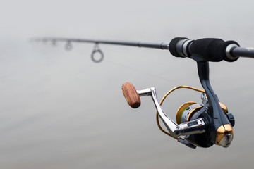 hand with spinning and reel on the evening summer lake