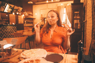 pretty plus size caucasian woman savoring and enjoying pizza in the pizzeria