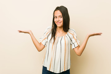 Young hispanic woman doubting and shrugging shoulders in questioning gesture.