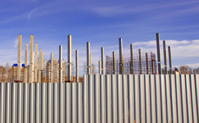 House construction. Poles behind the fence.