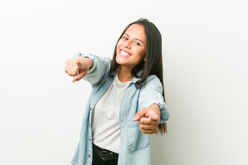 Young hispanic woman cheerful smiles pointing to front.