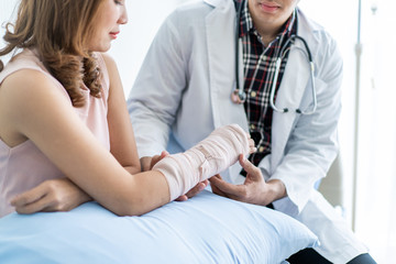 Asian woman talking to doctor in hospital about her broken arm.
