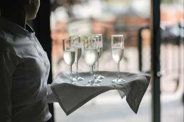 Elements of decor on the wedding ceremony. Waitress hold tray with champagne glasses