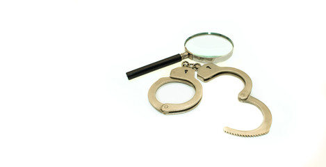 Magnifier and handcuffs on a white background