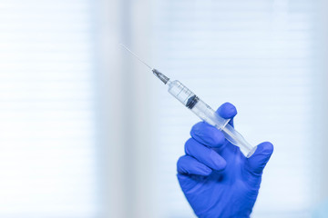 The doctor's gloved hand holds a syringe to make the vaccination