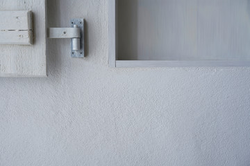 White wall with part of empty shelf and wooden white shutter