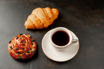 Coffee and croissant, bun on a stone table. morning breakfast