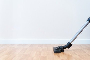 Modern vacuum head on wooden floor with copy space, housekeeper cleaning a room by using vacuum.