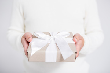 Christmas or Valentine's day concept - gift box in male hands over gray