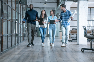 On the way to business meeting. Full length of young modern people in smart casual wear having a discussion while walking through the office