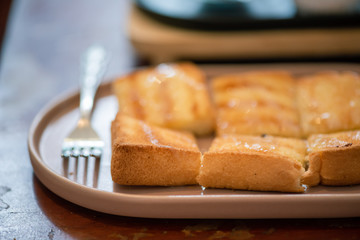 Butter baked bread topped with delicious milk and sugar by using a fork to eat in retro coffee shop.