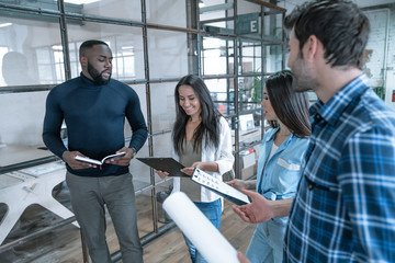 Best team ever. Group of young multi ethnic business people in smart casual wear working together and smiling while standing in the middle of the office