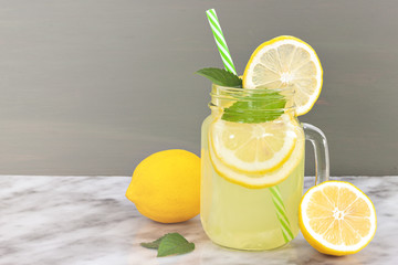 Lemon lemonade in mason jar glass ofwith lemons and straw on tab - Powered by Adobe