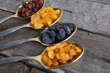 raisins in metal spoons on wooden table