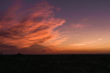 Magnifiques nuages de couleur orange et rose lors d'un coucher de soleil au dessus d'une plage