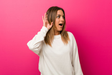 Fototapeta premium Young authentic charismatic real people woman against a wall trying to listening a gossip.
