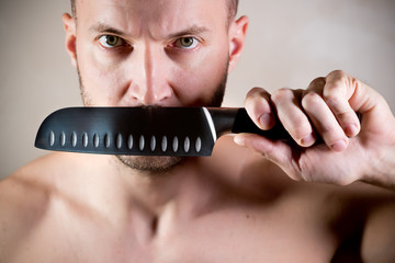 stern man closes his mouth with a kitchen knife