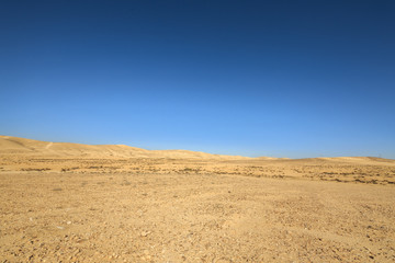 Far hills in desert under blue sky - obrazy, fototapety, plakaty