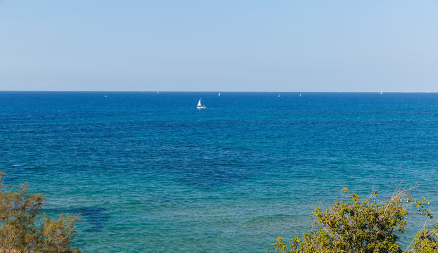 Small white yacht with a sail on Mediterranean Sea
