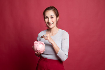 Asian woman with coin and pig coin bank.