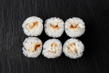 Maki Sushi Rolls with eel on black stone on dark background. Sushi menu. Japanese food. Closeup of delicious japanese food with sushi roll. Horizontal photo
