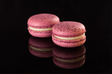 two macarons on a black table. Flash photo. Space for text. Gorizontal. Splash