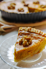 Pumpkin homemade vegan pie and spices cinnamon, anis, orange pumpkins with yelllow dry autumn leaves decor on dark table background.