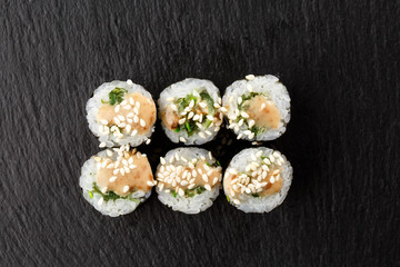 Maki Sushi Rolls with wakame and nut sauce on black stone on dark background. Sushi menu. Japanese food. Closeup of delicious japanese food with sushi roll. Horizontal photo