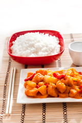 Sweet and sour chicken with bell pepper and pineapple. White rice on background