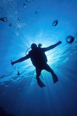 Fototapeta na wymiar Scuba diver in the blue water descending in to the depth