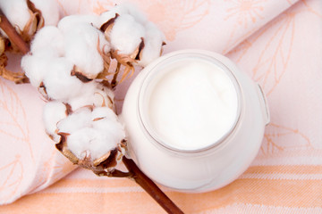 Sour cream in a jar on a beige background close-up on soft beige textile