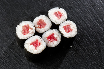 Maki Sushi Rolls with tuna on black stone on dark background. Sushi menu. Japanese food. Closeup of delicious japanese food with sushi roll. Horizontal photo