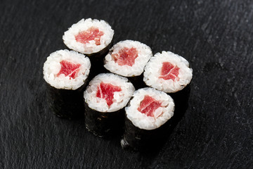 Maki Sushi Rolls with tuna on black stone on dark background. Sushi menu. Japanese food. Closeup of delicious japanese food with sushi roll. Horizontal photo