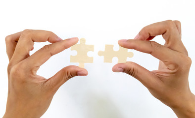 Hands female  merging 2 jigsaw puzzle pieces against isolated on white background, connection concept business partners combining