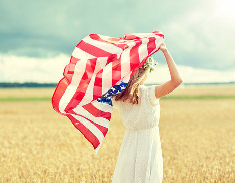 country, patriotism, independence day and people concept - happy young woman in white dress with national american flag on cereal field