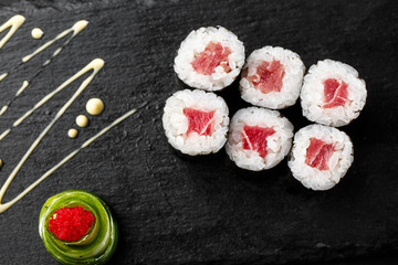 Maki Sushi Rolls with tuna on black stone on dark background. Sushi menu. Japanese food. Closeup of delicious japanese food with sushi roll. Horizontal photo